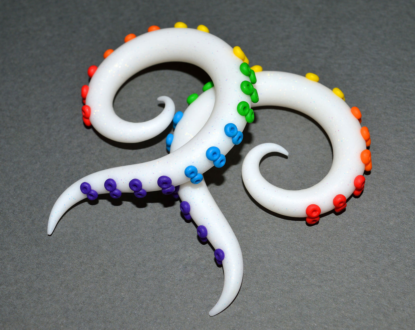 I made these tentacle earrings with glitter white polymer clay and rainbow suction cups. Fake tentacle ear gauges by artist Tania Chernova. I can also make earrings for stretched/gauged earlobes. Unique handmade spiral earrings that look like octopus tentacles. Tentacle gauges octopus plugs kraken earrings.