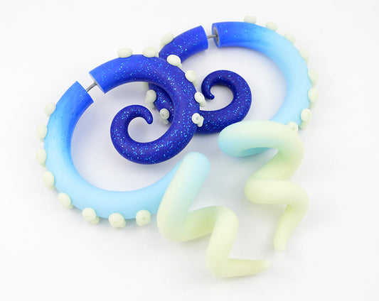 Artisan pastel goth octopus tentacle earrings by Tania Chernova. Sparkle glitter blue light blue glow in the dark yami kawaii earrings with glow suction cups, handmade glow in the dark earrings. Green glow in the dark fake gauge earrings and actual ear gauges ear plugs. Unique fake body jewelry tapers tunnels stretchers.