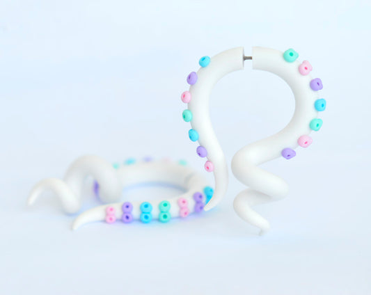 White tentacle earrings with pastel suction cups pastel goth accessory fake gauges and real ear plugs for kawaii goth. White octopus earrings with dots in mint, light pink, light purple, light blue.