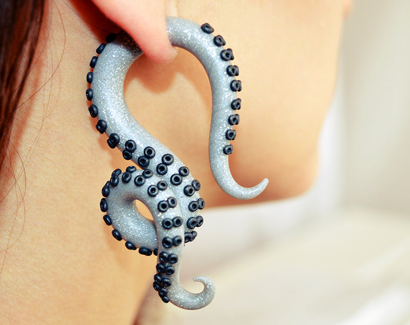 Handmade grey glitter tentacle earrings with black suction cups, unique fake gauges by Tania Chernova. Octopus earrings with white sparkle light effect, fake ear plugs with glitter. Handmade body jewelry. Can be used as cosplay earrings for cosplay costumes or just for lovers of unique earrings. These fake gauge earrings looks good with gold glitter pink glitter silver glitter and black glitter accessories and glitter makeup. Glitter eye makeup will look better with these unique earrings.